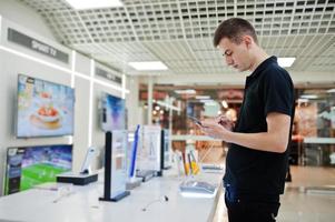 vendeur homme consultant professionnel en téléphonie mobile dans un magasin de technologie ou un magasin tenant un nouveau smartphone à portée de main. photo