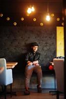 confiant jeune homme indien en chemise noire assis au café. photo