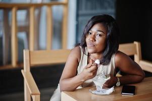 fille afro-américaine assise au café et mangeant des glaces. photo