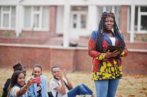 groupe de cinq étudiants africains qui passent du temps ensemble sur le campus de la cour universitaire. amis afro noirs qui étudient. thème de l'éducation. photo