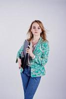 fille blonde élégante en veste et jeans avec carnet de notes et ordinateur portable à portée de main sur fond blanc en studio. photo