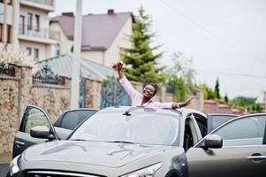 riche femme africaine d'affaires en voiture suv argentée sur le toit ouvrant s'amusant avec de la bière à portée de main. photo