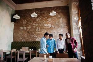 groupe de quatre hommes sud-asiatiques posés lors d'une réunion d'affaires au café. indiens ayant la conversation. photo