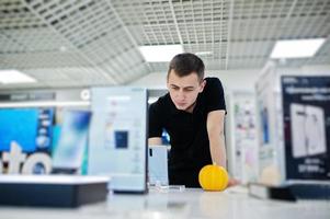 vendeur homme consultant professionnel en téléphonie mobile dans un magasin de technologie ou un magasin tenant un nouveau smartphone à portée de main. photo