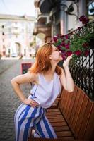 jolie femme rousse à lunettes posant dans la rue de la ville de printemps. photo