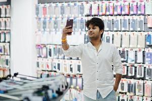 acheteur client indien dans un magasin de téléphonie mobile faisant du selfie sur son nouveau smartphone avec étui. concept de peuples et de technologies d'asie du sud. magasin de téléphonie mobile. photo