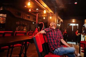 un homme asiatique fume du narguilé et se repose au bar-salon. photo