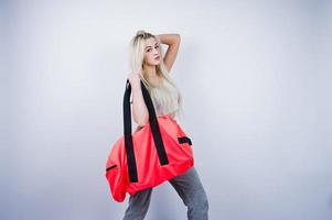 fille sportive blonde avec grand sac de sport posé au studio sur fond blanc. photo