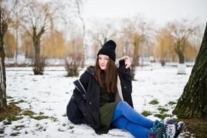 jeune fille porte un long sweat-shirt vert, un jean et un couvre-chef noir avec sac à dos en journée d'hiver. photo