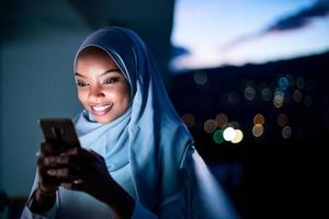 jeune femme musulmane dans la rue la nuit à l'aide de téléphone photo