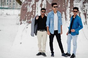 groupe de trois jeunes hommes indiens décontractés en lunettes de soleil posés le jour de l'hiver. photo