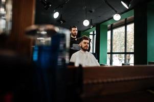 bel homme barbu au salon de coiffure, coiffeur au travail. photo