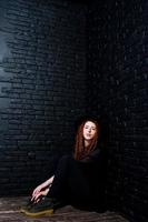 tournage en studio d'une fille en noir avec des dreads et un chapeau sur fond de briques. photo