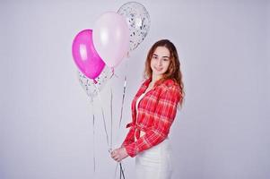 jeune fille en chemise à carreaux rouge et pantalon blanc avec des ballons sur fond blanc en studio. photo