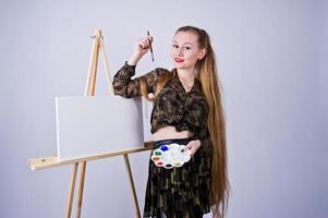 belle femme artiste peintre avec pinceaux et toile à l'huile posant en studio isolé sur blanc. photo