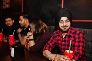 groupe d'amis indiens s'amusant et se reposant à la discothèque, buvant des cocktails. photo