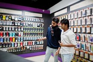 deux indiens mans client acheteur au téléphone mobile faisant selfie par bâton monopode. concept de peuples et de technologies d'asie du sud. magasin de téléphonie mobile. photo