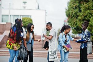 groupe de cinq étudiants africains qui passent du temps ensemble sur le campus de la cour universitaire. amis afro noirs qui étudient. thème de l'éducation. photo