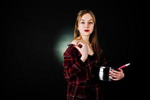 jeune femme au foyer en robe à carreaux avec casserole et cuillère de cuisine isolée sur fond noir. photo