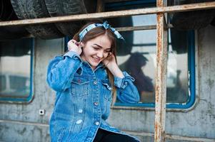 jeune fille hipster en veste jeans et foulard à la zone de montage des pneus. photo