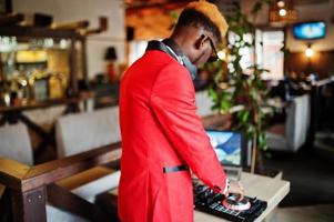 mode homme afro-américain modèle dj en costume rouge avec contrôleur dj. photo