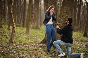 histoire d'amour d'un couple multiracial cool dans la forêt printanière. demande en mariage homme arabe à fille européenne. photo