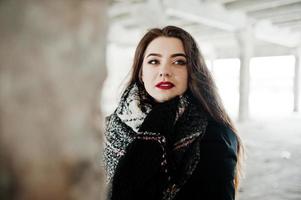 brune élégante fille décontractée en écharpe contre la place de l'usine abandonnée. photo