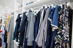 ensemble de vêtements colorés bleus féminins sur les étagères du magasin de vêtements toute nouvelle boutique moderne. photo