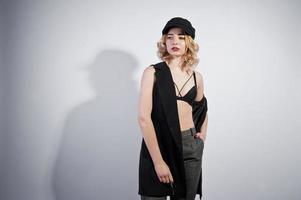 portrait en studio de fille blonde en vêtements noirs et casquette sur fond blanc. photo