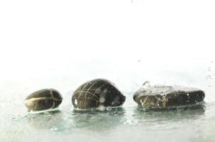 pierres zen humides isolées avec des éclaboussures de gouttes d'eau photo