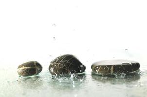 pierres zen humides isolées avec des éclaboussures de gouttes d'eau photo