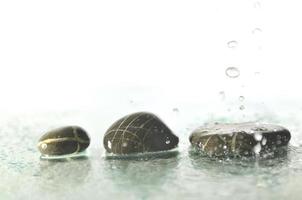 pierres zen humides isolées avec des éclaboussures de gouttes d'eau photo