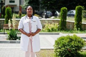 femme médecin afro-américaine en blouse de laboratoire avec stéthoscope en plein air. photo