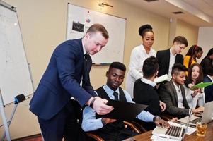 jeunes créatifs multiraciaux dans un bureau moderne. groupe de jeunes gens d'affaires travaillent avec un ordinateur portable, une tablette. équipe de pigistes à succès dans le coworking. photo