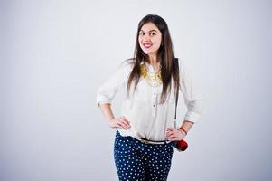 portrait d'une jeune femme en pantalon bleu et chemisier blanc posant avec mégaphone en studio. photo