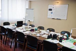 intérieur de bureau d'affaires moderne contenant des tables et des chaises, un ordinateur portable, un appareil photo et des fournitures de bureau sans employés.