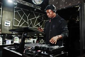 un dj afro-américain joue de la musique sur les platines de la discothèque. photo