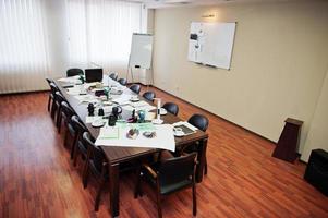 intérieur de bureau d'affaires moderne contenant des tables et des chaises, un ordinateur portable, un appareil photo et des fournitures de bureau sans employés.