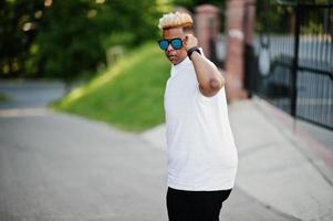 garçon musulman arabe élégant avec à l'origine des cheveux et des lunettes de soleil posés dans les rues. photo