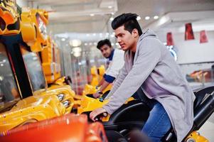 deux gars asiatiques s'affrontent sur la machine de simulateur de course de moto de jeu d'arcade de speed rider. photo