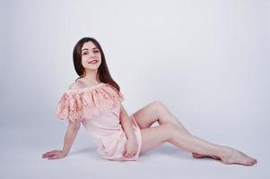 portrait d'une femme à la mode en robe rose assise et posant sur le sol dans le studio. photo