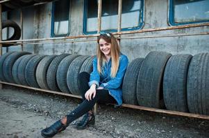 jeune fille hipster en veste jeans et foulard à la zone de montage des pneus. photo