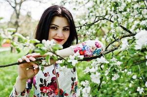 portrait de printemps d'une jeune fille brune au jardin de fleurs vertes. photo