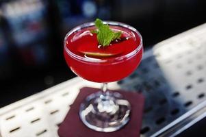 cocktail rouge alcoolisé à la menthe sur table de bar.