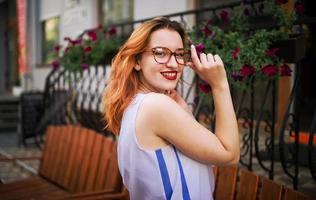 jolie femme rousse à lunettes posant dans la rue de la ville de printemps. photo