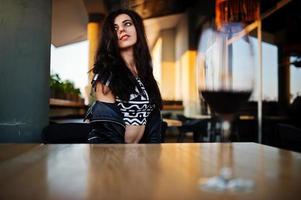 jeune femme frisée dégustant son vin dans un bar. photo