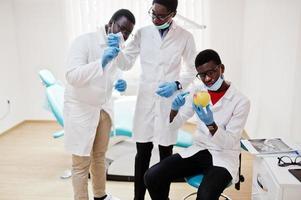 trois collègues médecins afro-américains dans une clinique dentaire avec une pomme. photo