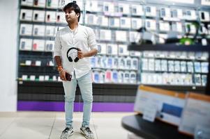 Acheteur client indien dans un magasin de téléphonie mobile avec des écouteurs sans fil se connectant à son smartphone. concept de peuples et de technologies d'asie du sud. magasin de téléphonie mobile. photo