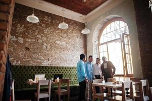 groupe de quatre hommes sud-asiatiques posés lors d'une réunion d'affaires au café. indiens ayant la conversation. photo