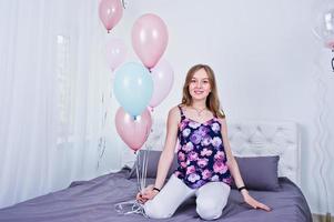 fille heureuse avec des ballons colorés sur le lit dans la chambre. célébrer le thème de l'anniversaire. photo